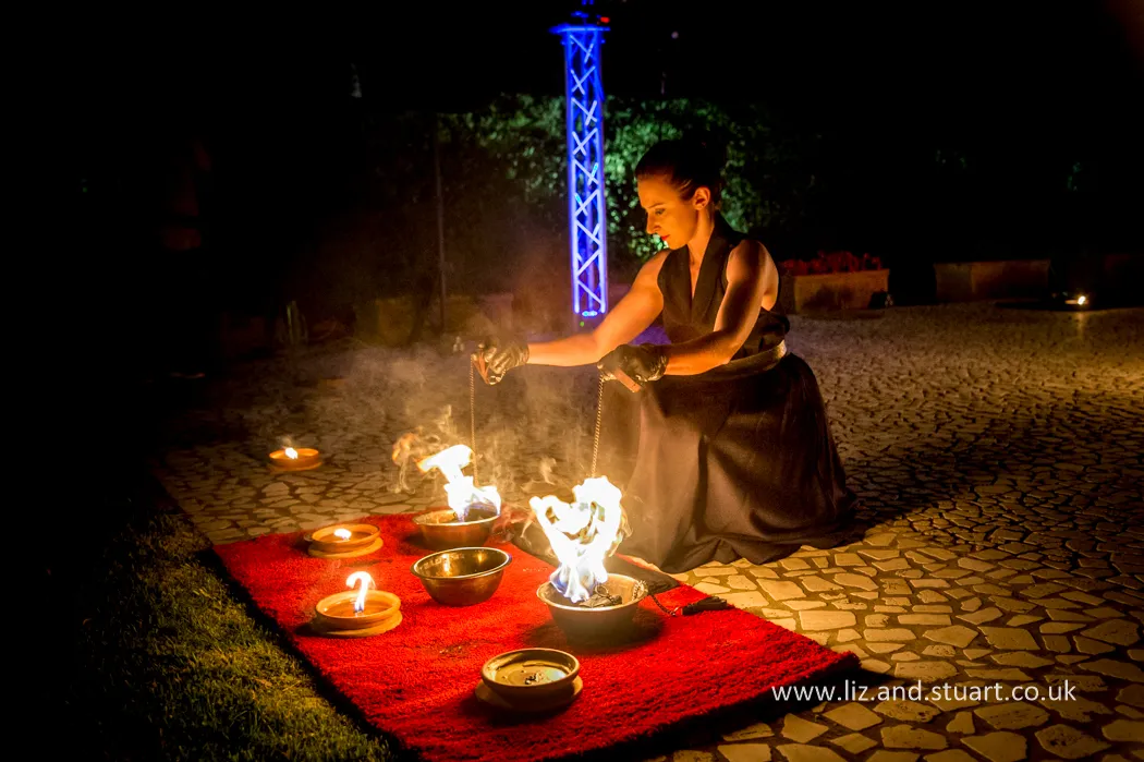 Performer di Lumen Invoco mentre allestisce uno spettacolo con fuoco per il matrimonio, sicuro, utilizzando moquette ignifughe e attrezzature certificate per proteggere il pavimento storico della villa.